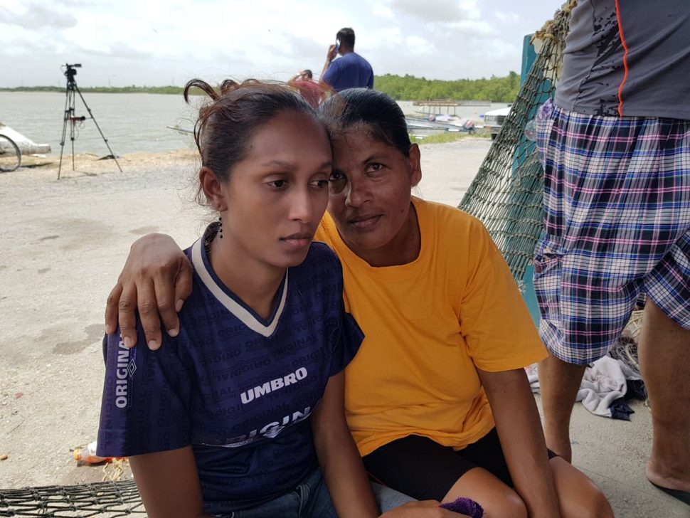 Relatives of the missing fishermen Sahidan Khan left,  wife of Anand Rampersad and Nazeema Ramdeo, mother of Shiva Ramdeo, right, console each other at the Orange Valley Fishing Depot yesterday. 