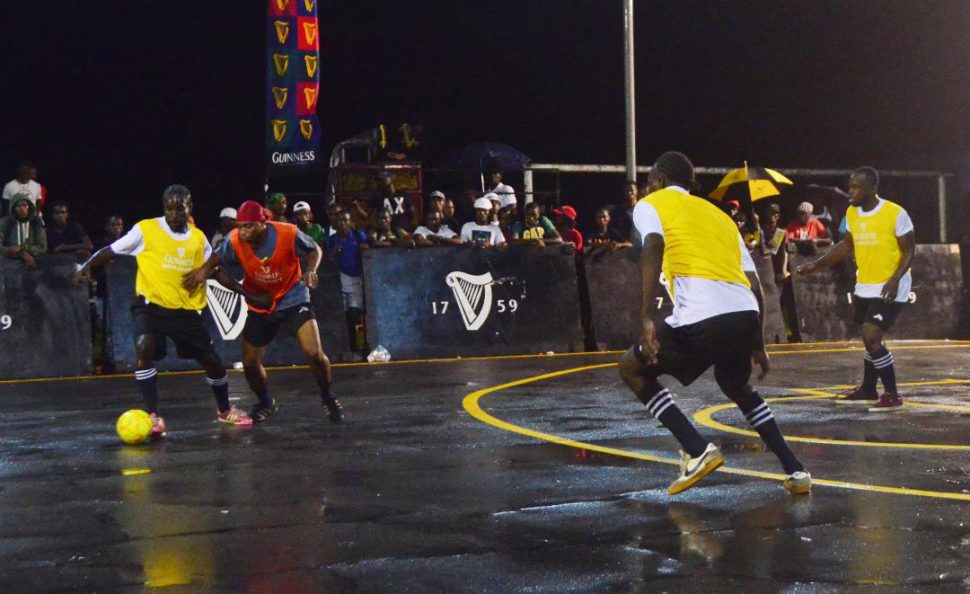 Jason Fredericks [left] of Queen Street Tiger Bay trying to maintain possession while being challenged by Dellon David of Smythe Street during their clash in the Guinness ‘Greatest of the Streets’ Georgetown Championship at the Burnham Court Saturday.
