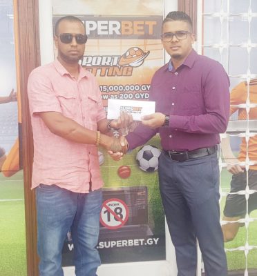 General Manager of SuperBet, Shrikant Kisoensingh (right) presents the company’s sponsorship pact to Rovin DeSouza, a representative of the Jumbo Jet Thoroughbred Racing Committee.