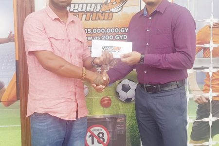 General Manager of SuperBet, Shrikant Kisoensingh (right) presents the company’s sponsorship pact to Rovin DeSouza, a representative of the Jumbo Jet Thoroughbred Racing Committee.