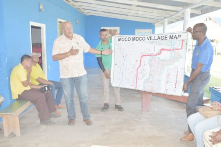 Dr. Richard Van West-Charles (standing at left) points to a map which was designed by a Moco Moco
villager and printed through GWI. (GWI photo) 