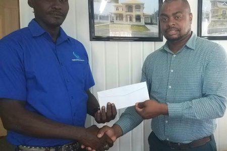 Senior Supervisor at R&D Engineering, Marvin Duke (left) hands over the sponsorship to Edison Jefford yesterday at the company’s North Road Office. 
