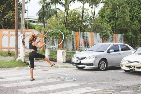 A street performer displays her skills with the hula hoops as she entertains persons at the traffic lights at the junctions of Camp and North Road. (Photo by Terrence Thompson)
