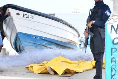 A police officer stands guard next to the body of fisherman Anand  Rampersad, 39 of Smith Street, Carapichiama after a search party recovered the body at 8.30am one and a half miles off Carli Bay.