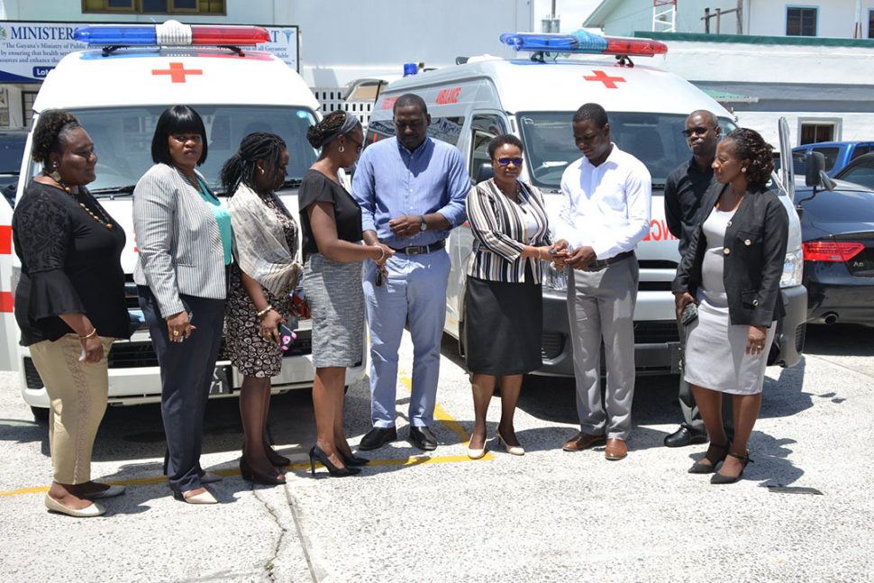 Minister of Public Health Volda Lawrence (fourth, from right) hands over the keys to the ambulance to Region Four’s RHO Dr Quincy Jones, while Director of Primary Healthcare Services Dr Ertenesia Hamilton (fourth, from left) hands over the keys to the ambulance to Region Three’s RHO Dr Cerdel McWatt. (DPI photo)