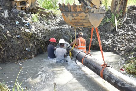 A breakage of a 14-inch main at Cemetery Road, resulted in the disruption of the water supply to Central Georgetown and its environs yesterday. Guyana Water Incorporated (GWI) said its technicians worked throughout Thursday night to repair the main. The situation was not rectified until yesterday afternoon. GWI spokesperson Leana Bradshaw told this newspaper that because the main was over a canal next to the cemetery, the company had to create two revetment dams, using nine truckloads of dirt, and pump out the water before it could assess exactly what had to be done. In photo, workers can be seen installing a repair sleeve on the pipeline. (Photo taken from GWI Facebook page)