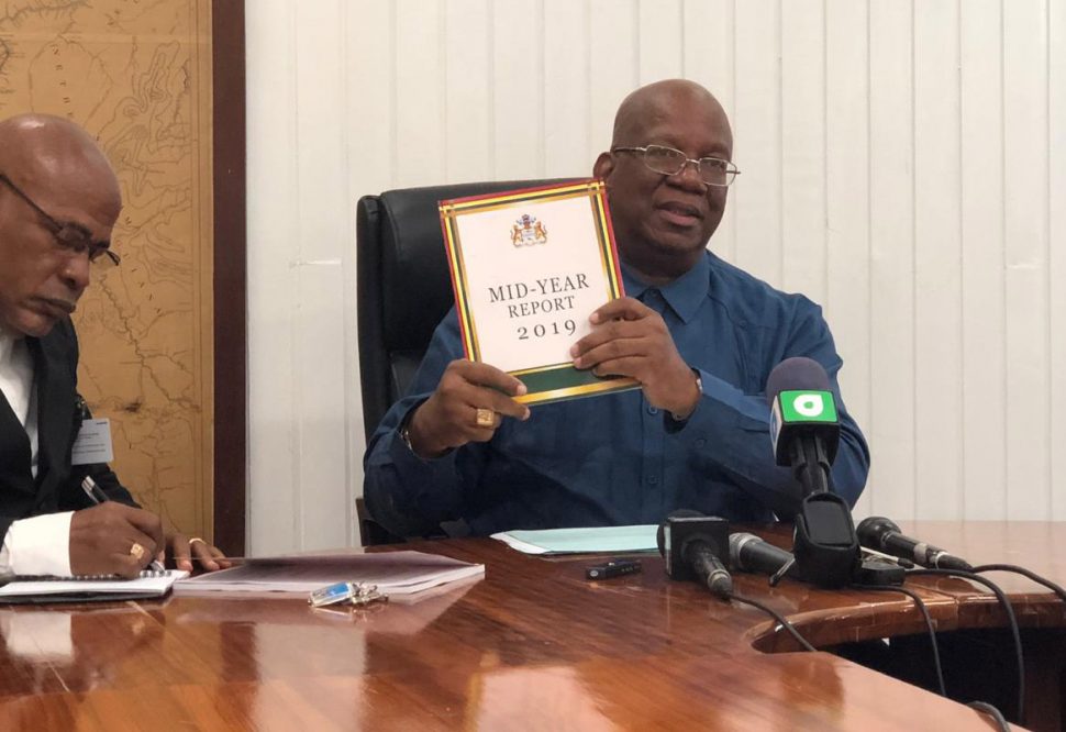 Minister of Finance Winston Jordan holding the mid-year report yesterday. 
