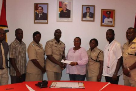 Superintendent Crystal Robinson (fourth, from right) receiving a sum of cash from Commissioner of Police (ag) Nigel Hoppie in the presence of other senior members of the Guyana Police Force. (Guyana Police Force photo)