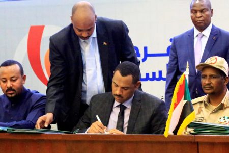 Deputy Chairman of the Sudanese Transitional Military Council, Mohamed Hamdan Dagalo, and Sudan’s opposition alliance coalition’s leader Ahmad al-Rabiah, sign a power sharing deal, as Ethiopia’s Prime Minister Abiy Ahmed witnesses, in Khartoum, Sudan, yesterday. (REUTERS/Nureldin Mohamed Abdallah)