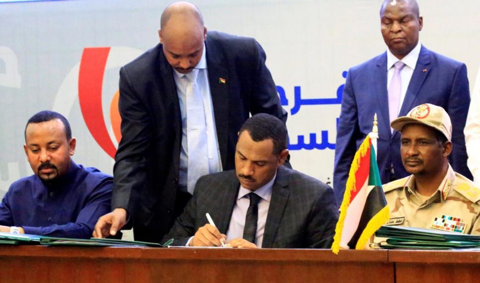 Deputy Chairman of the Sudanese Transitional Military Council, Mohamed Hamdan Dagalo, and Sudan’s opposition alliance coalition’s leader Ahmad al-Rabiah, sign a power sharing deal, as Ethiopia’s Prime Minister Abiy Ahmed witnesses, in Khartoum, Sudan, yesterday. (REUTERS/Nureldin Mohamed Abdallah)