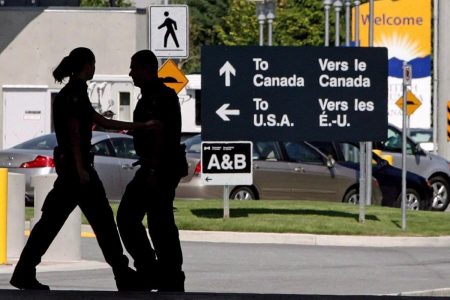 Canadian border guards are silhouetted as they replace each other at an inspection booth at a crossing on the Canada-U.S. border. (Darryl Dyck/Canadian Press)