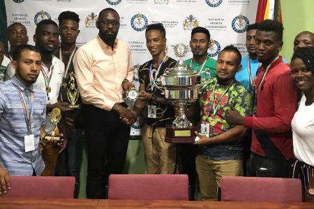 Kenrick Carrington, Captain of the Guyana National Deaf Football Team collecting the NSC Award from the Director of Sports Christopher Jones in the presence of his teammates. The victorious team pose with their spoils.
