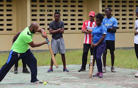 Coach Anthony D’Andrade sharing batting tips for the youths on the Berbice High School Tarmac 
