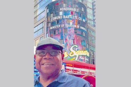 Minister of Tourism Edmund Bartlett in New York on Sunday to watch the city's famous Times Square pay tribute to Jamaican culture, in the background. (contributed)