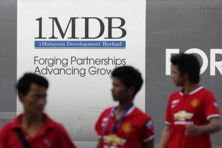 Men walk past a 1Malaysia Development Berhad (1MDB) billboard at the fund's flagship Tun Razak Exchange development in Kuala Lumpur March 1, 2015. REUTERS/Olivia Harris/File photo