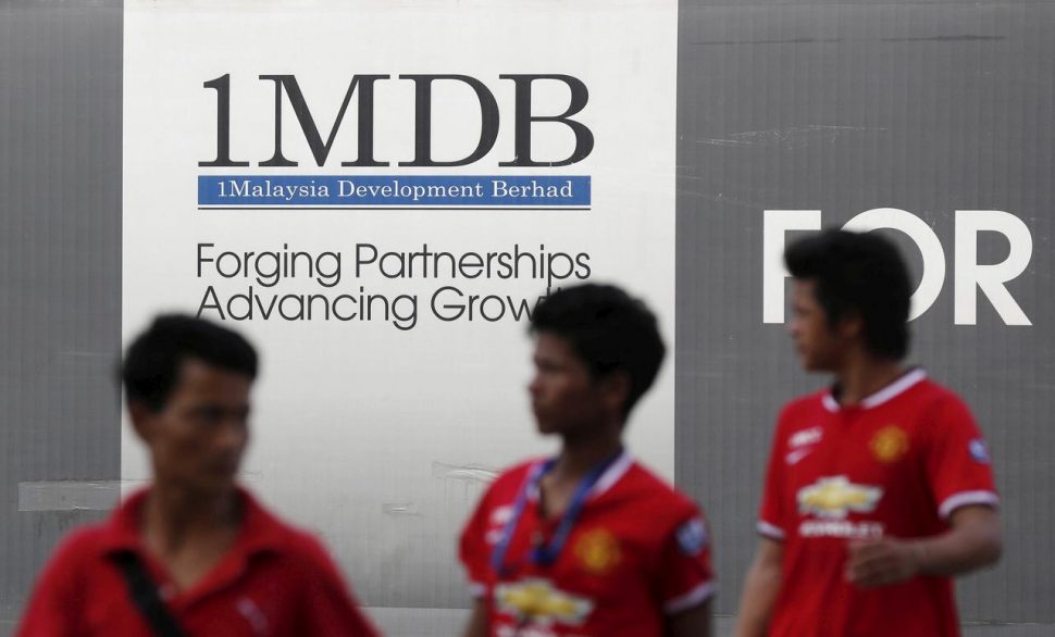 Men walk past a 1Malaysia Development Berhad (1MDB) billboard at the fund’s flagship Tun Razak Exchange development in Kuala Lumpur March 1, 2015. REUTERS/Olivia Harris/File photo