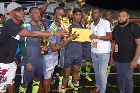 Hard-Knocks captain Clive Nobrega collects the prize from New Era Entertainment Co-Director Aubrey Major Jr., in the presence of his teammates after defeating NK Ballers to capture the Mohamed’s Enterprise Futsal Championship.
