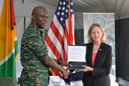 Director General of the Civil Defence Commission (CDC) Lieutenant Colonel Kester Craig receives a certificate documenting the items donated by the United States Department of Defense Humanitarian Assistance Program from US Ambassador to Guyana,  Sarah-Ann Lynch. (Ministry of the Presidency photo)