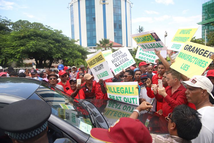 Members of the Opposition People’s Progressive Party swarmed the vehicle in which Minister of Foreign Affairs Dr Karen Cummings was travelling at the Pegasus Hotel yesterday.  The Minister was forced to turn away from the entrance to the venue where President David Granger was addressing members of the Private Sector. (Terrence Thompson photo) 