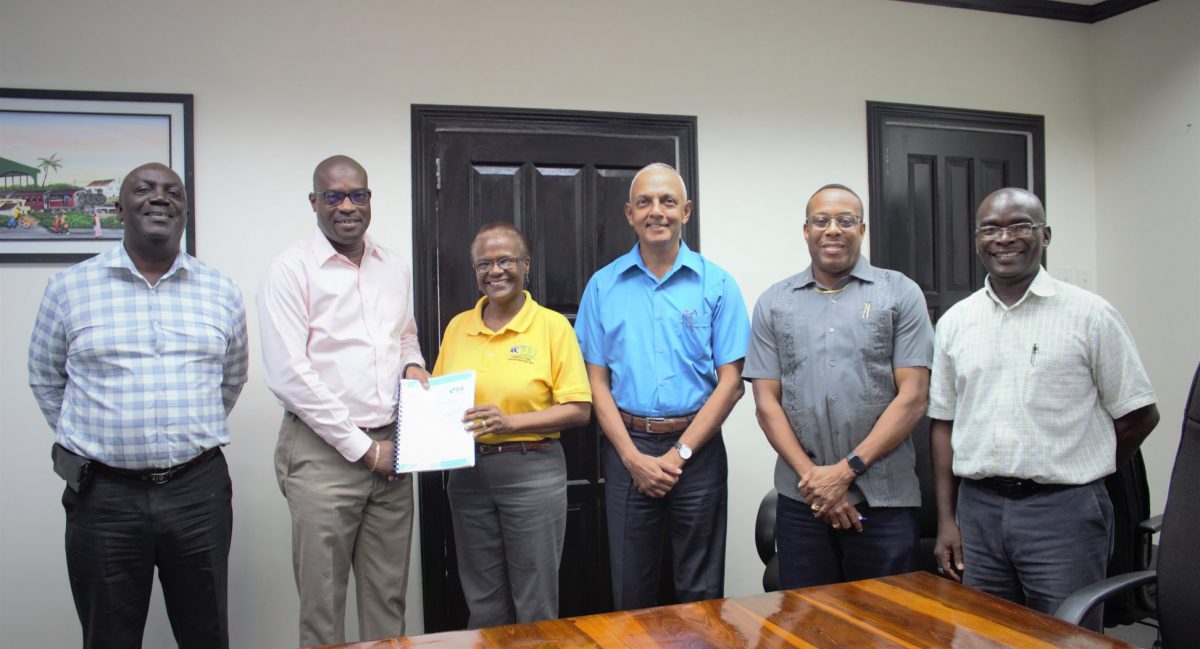 Minister of Public Infrastructure David Patterson hands the contract over to the B & J Civil Works representative following yesterday’s signing in the presence of other officials, including Communities Minister Ronald Bulkan. (Ministry of Public Infrastructure photo) 
