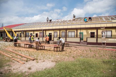 Fast fix: Workers repairing the roof of Mahdia Primary School after the zinc sheets were ripped off by winds last Friday. See story on page 17 (Department of Public Information photo) 