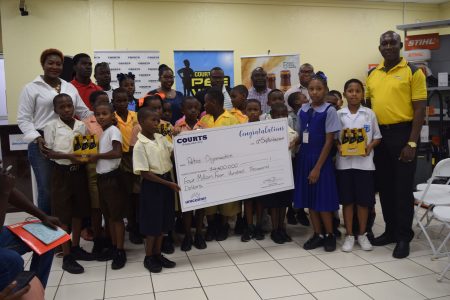 Petra Organisation Co-Director Troy Mendonca [centre] posing with several students from the participating schools at the official launch of the 8th Courts Pee Wee U-11 Football Championship. Also in the photo are representatives from Banks DIH Limited and Courts Guyana.
