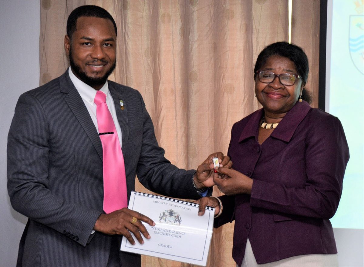Alvin Doris (left), Environmental, Policy and Education Coordinator, Department of Environment hands over the modified Curriculum Guides to  Jennifer Cumberbatch, Director, National Centre for Educational Resource Development. (Ministry of the Presidency photo)