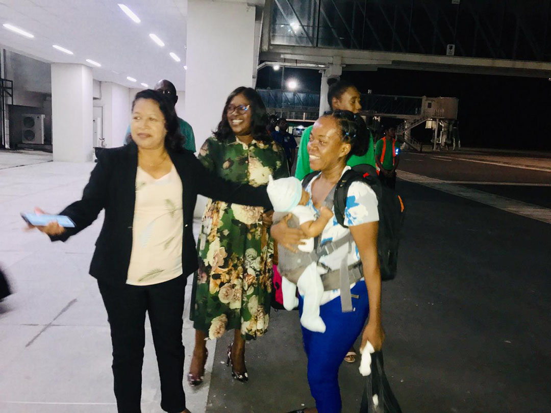 Minister of State Dawn Hastings (left) welcomes home Hurricane Dorian survivor Mrs Grimmond and her infant at the Cheddi Jagan International Airport, Timehri last night as Minister of Foreign Affairs Dr Karen Cummings looks on.