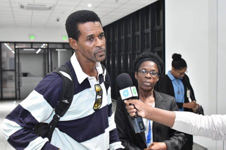 Cecil Simon speaking to the media about his hurricane experience in The Bahamas. Looking on is his wife, Olive. (Ministry of the Presidency photo)