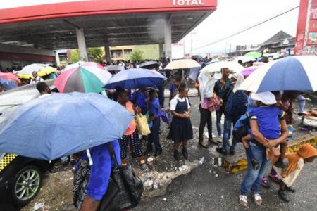 Commuters stranded in the rain on North Odeon Avenue in the Corporate Area yesterday due to the withdrawal of Jamaica Urban Transit Company buses.