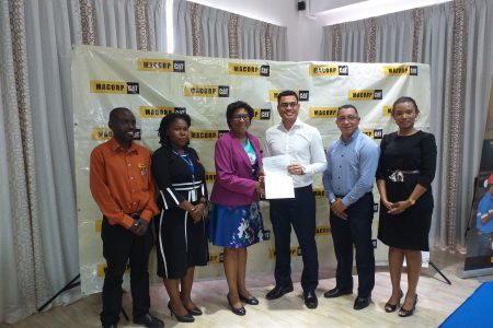 Minister of Public Telecommunications, Catherine Hughes (third from left) and MACORP CEO  Guillermo Escarraga holding the MoU. (Ministry of Public Telecommunications photo)