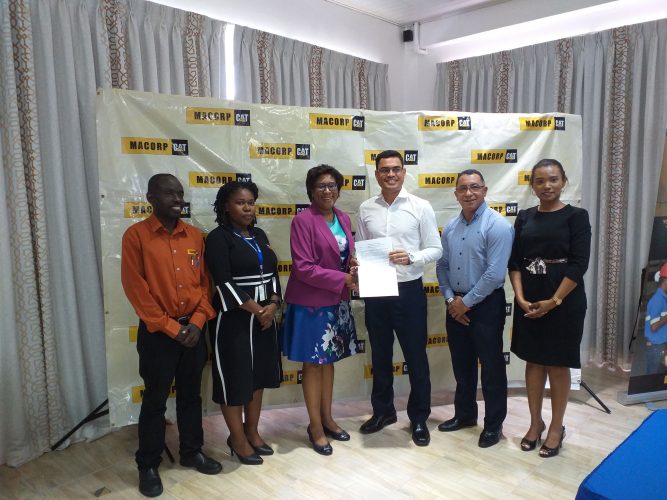 Minister of Public Telecommunications, Catherine Hughes (third from left) and MACORP CEO  Guillermo Escarraga holding the MoU. (Ministry of Public Telecommunications photo)