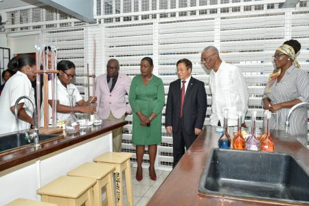 President David Granger (second from right), China’s Ambassador to Guyana Cui Jianchun (third from right), Minister of Education Dr. Nicolette Henry (second from left), Chief Education Officer, Dr. Marcel Hutson (left) and Principal CPCE, Viola Rowe look on as students conduct an experiment. (Ministry of the Presidency photo)
