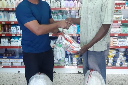 Mike’s Pharmacy’s Wayne Jones (right) presents coach Zaheer Mohammed with the gear.
