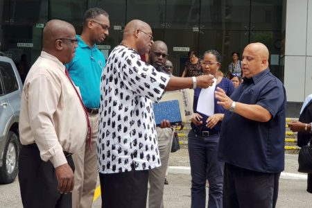 General Secretary of the National Trade Union Centre of T&T (NATUC) Michael Annisette, second from left, shares the letter to members outside the Attorney General’s office, Government Campus, Port-of-Spain, yesterday
