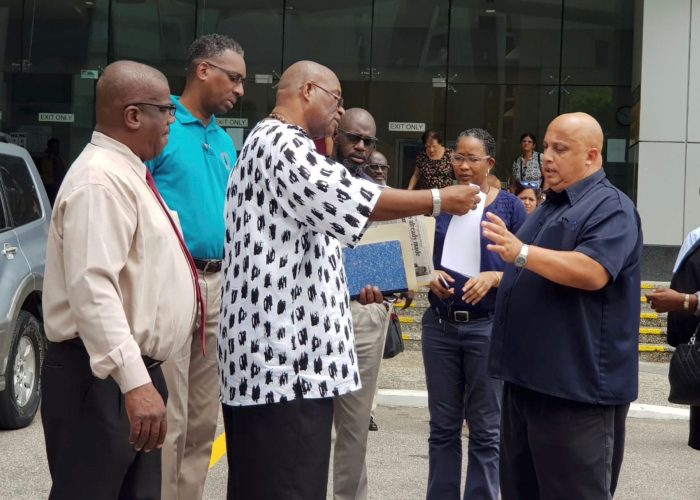 General Secretary of the National Trade Union Centre of T&T (NATUC) Michael Annisette, second from left, shares the letter to members outside the Attorney General’s office, Government Campus, Port-of-Spain, yesterday