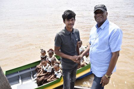 Tulsi Persaud (left) hands over the boat to Joseph Harmon. (Ministry of the Presidency photo)