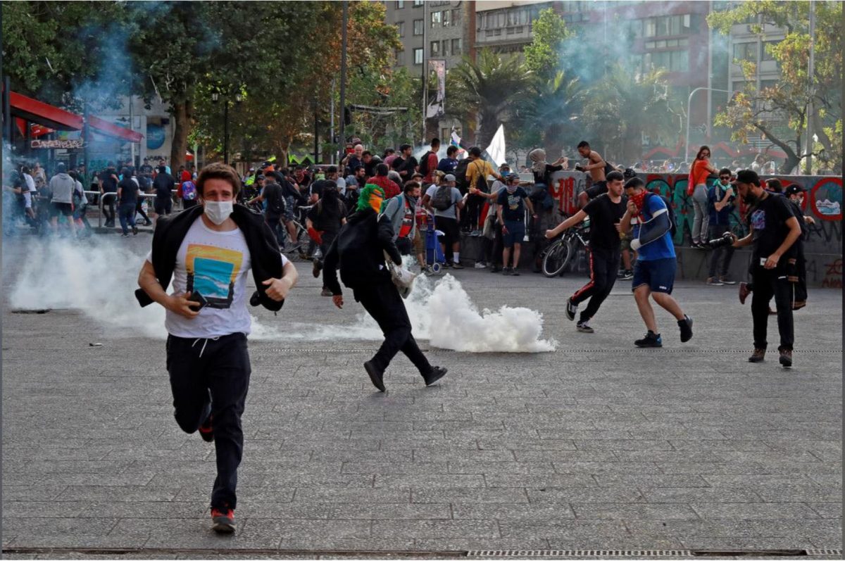 Demonstrators run from tear gas during a protest against Chile’s state economic model in Santiago yesterday. (REUTERS/Henry Romero)