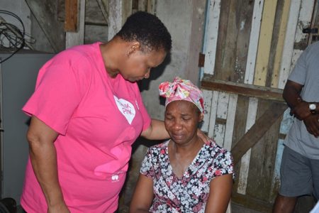 Public Health Minister Lawrence consoles mother of Nurse Reddock, Merelene Niles at her Amelia’s Ward home today. (Department of Public Information)