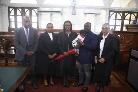 New attorney Tifaine Rutherford (at centre) along with her father, Audwin Rutherford (at left), Chief Justice (ag) Roxane George (second, from left), her partner Dennis Adams and their daughter, and petitioner Latchie Rahamat. (Terrence Thompson photo)  