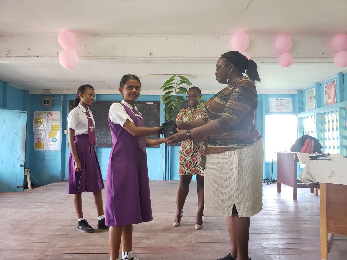 Genevieve Allen presenting a student of La Bonne Intention Secondary School with a plant.