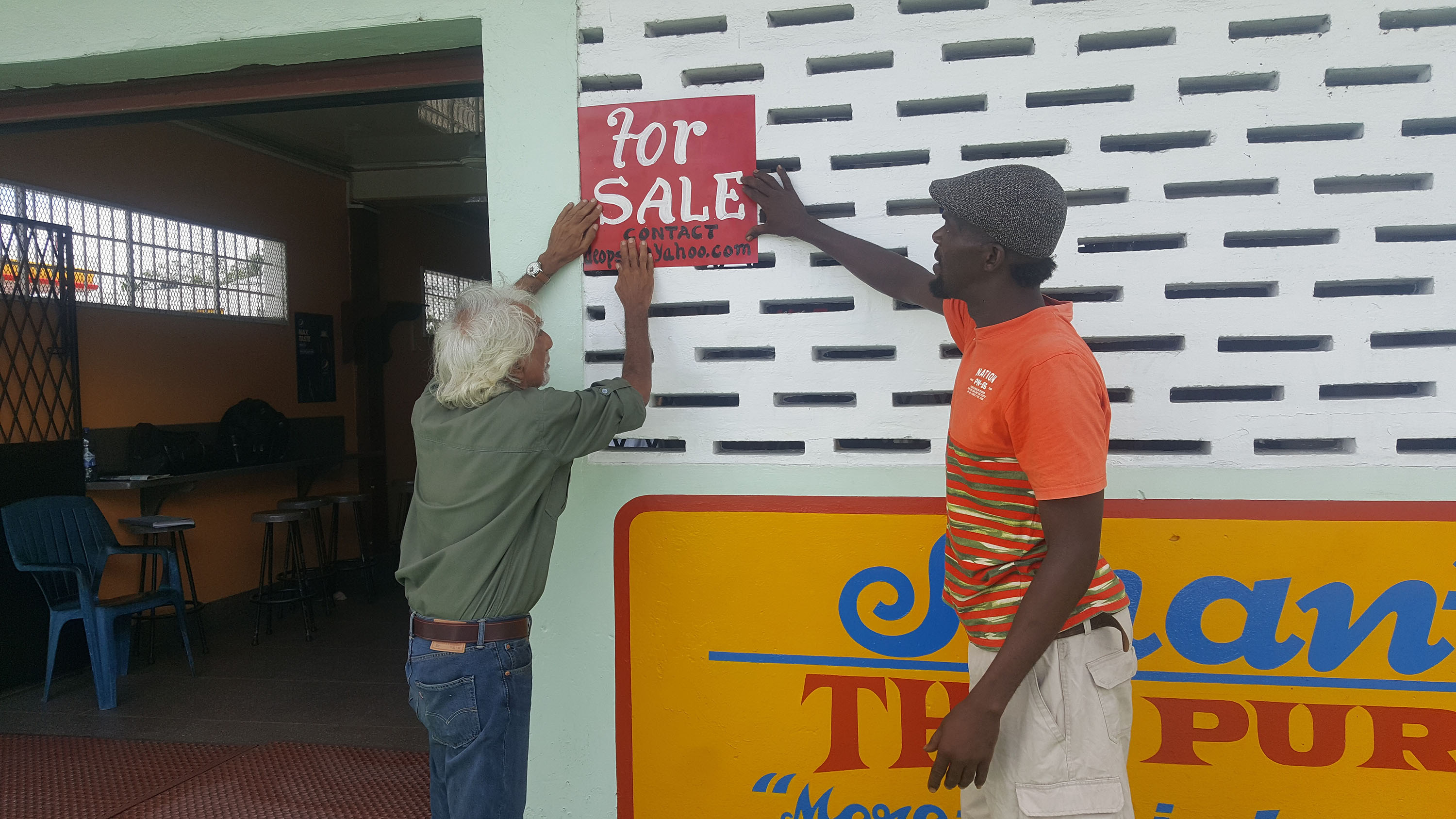 Deodat Persaud erecting a ‘For Sale’ sign on the building. 