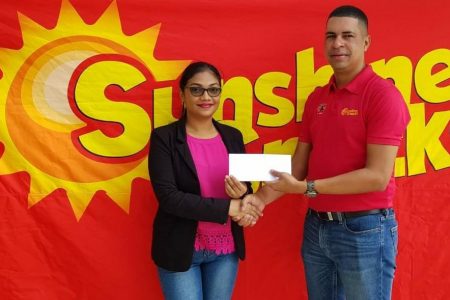 Sunshine Snacks country manager Jeranzee Marques handing over the prize to CPL promotion winner Savitri Basdeo