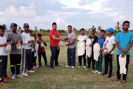 West Indian Sports Complex proprietor Javed Khan presents President of the Ogle Community Centre Cricket Club Ashmul Ali with cricketing gear and uniforms.
