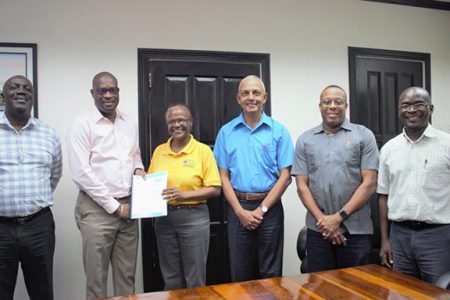 Minister of Public Infrastructure David Patterson (second from left) hands over the Kato hydro project contract to the B & J Civil Works representative following the signing in the presence of other officials, including Communities Minister Ronald Bulkan. (Ministry of Public Infrastructure photo)