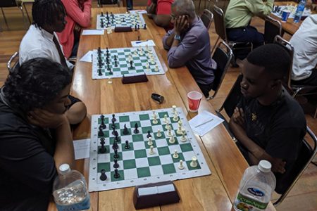 National player Taffin Khan (left) during his fourth-round match with Davion Mars at the National Resource Centre on Tuesday evening. Sitting alongside Khan is Frankie Farley (with tie), President of the Guyana Chess Federation. His opponent is national player Loris Nathoo. (Photo: John Lee)