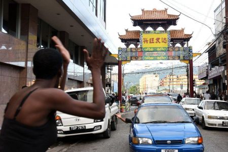 STANDING TALL: Charlotte Street vendor Crystal Daniel gestures as she looks at the China Town arch placed across Charlotte Street near the Park Street intersection yesterday in Port of Spain.