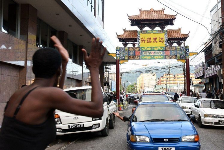 STANDING TALL: Charlotte Street vendor Crystal Daniel gestures as she looks at the China Town arch placed across Charlotte Street near the Park Street intersection yesterday in Port of Spain.