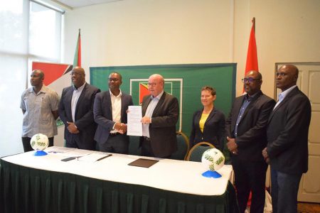 DFA President Jesper Moller [center] and GFF President Wayne Force [3rd from left] displaying the signed development MoU following the official ceremony. Also in the photo from left to right are 1st Vice President Bruce Lovell, CONCACAF Senior Project Manager Howard McIntosh, UEFA Head of International Relations Eva Pasquier, 2nd Vice President Rawlston Adams and General Secretary Ian Alves.