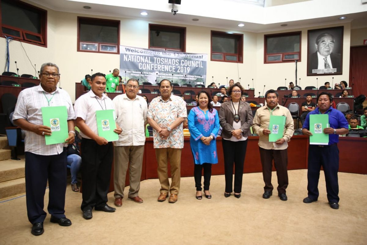 Some of the toshaos display the certificates of titles for their village lands yesterday while standing alongside government ministers yesterday (DPI photo) 